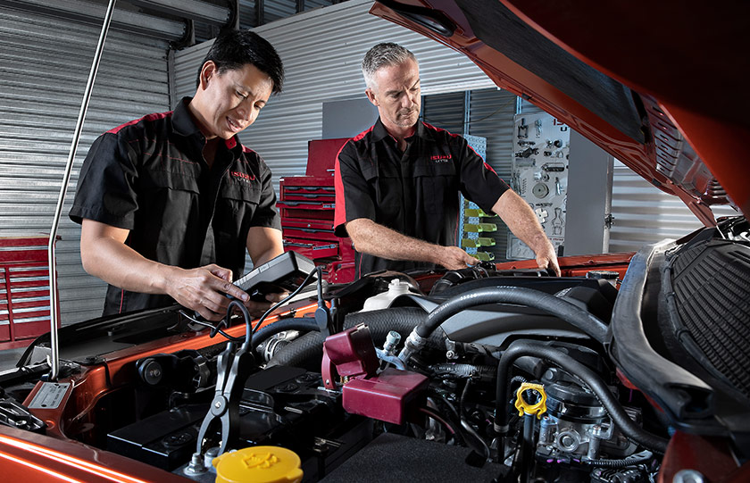 Two Isuzu Ute Service Plus technicians service the engine of an Isuzu Ute