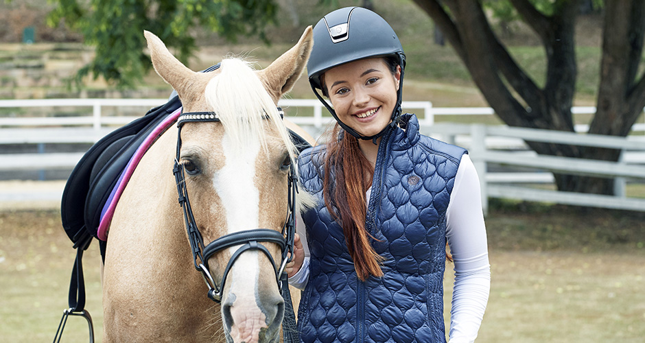 Headshot of Em Wayman standing next to a horse